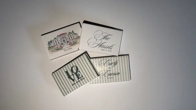 Four custom wedding matchboxes with a venue illustration, calligraphy monogram, and green striped LOVE Philadelphia design