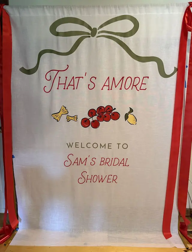 That's Amore fabric welcome banner for a bridal shower with illustrated lemons and cherries and red ribbon ties